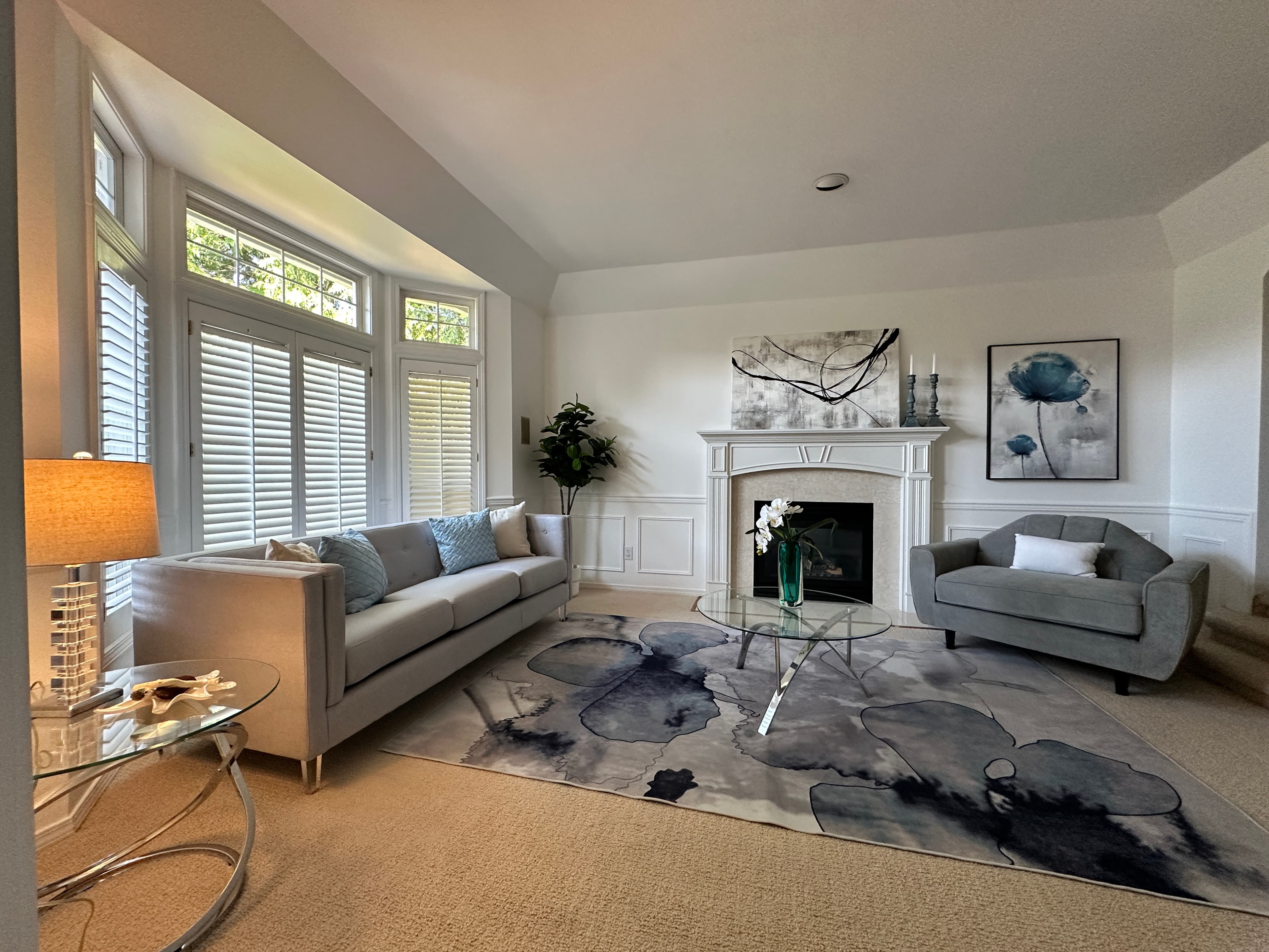 Living Room — Gray Sofas, Blue Abstract Rug, White Fireplace & Shuttered Bay Windows