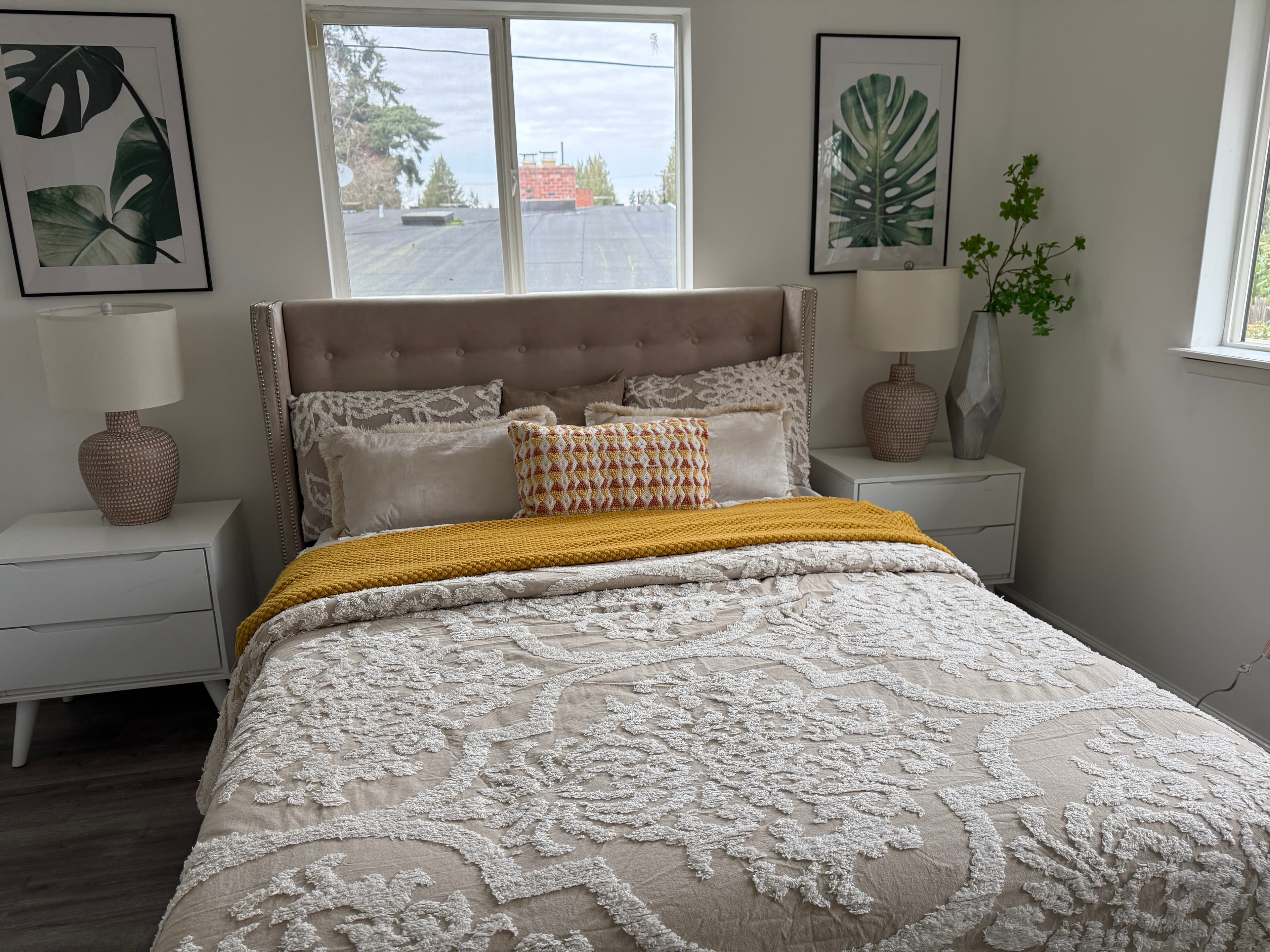 Primary Bedroom — Taupe Wingback Headboard, Floral Quilt & Monstera Art